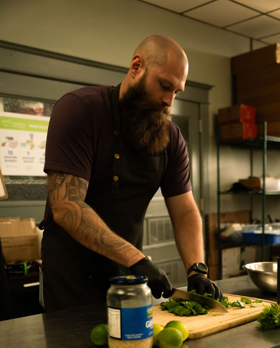 Man with tattoos preparing food in a kitchen setting